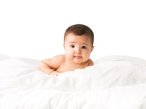 Close-up of a happy cute baby girl lying on the bed