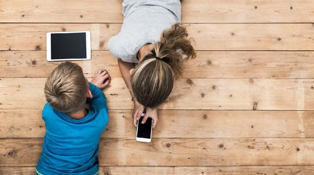 Top view image of two kids lying on the floor and playing with tablet and smartphone watching movie or gaming. Mockup or template for web or application design.