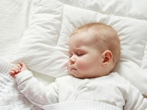 Close-up of sleeping baby hand in the mother's hand on the bed. New family and baby sleep concept