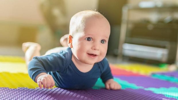 Charming little baby boy 6 months smiling and looking at the camera in home