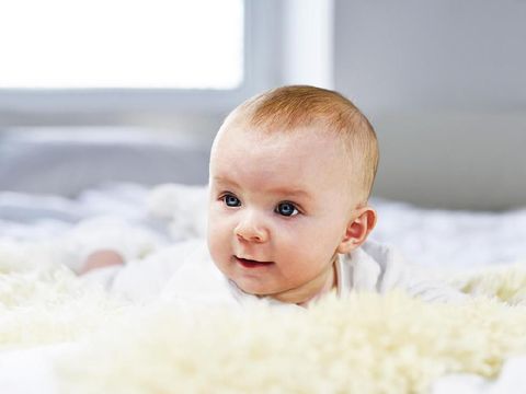 Funny baby lying in bed looking at camera. Childhood. Good morning.