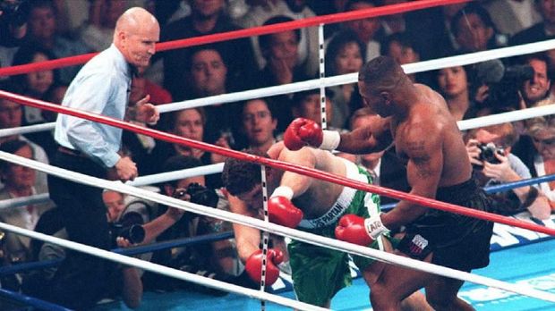 Peter McNeeley falls to the canvas for the second time in the first round after being hit by Mike Tyson (R) as referee Mills Lane (L) looks on 19 Aug during Tyson's comeback fight at the MGM Grand Garden in Las Vegas, NV. Tyson won by disqualification 89 seconds into the first round.  AFP PHOTO (Photo by Steve MACK / AFP)