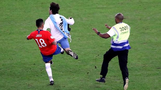 Gonzalo Jara (kiri) menendang fan penyusup di lapangan Stadion Maracana. (