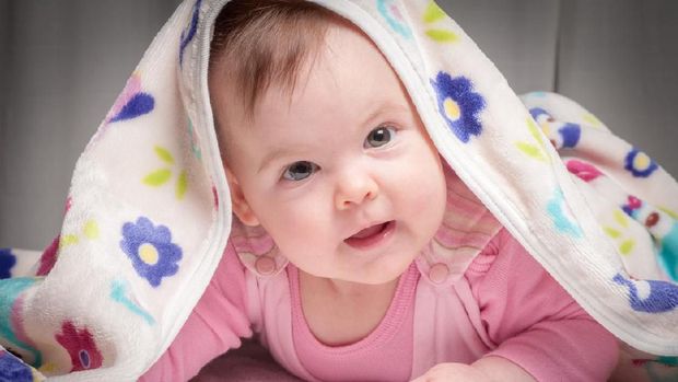 Smiling baby after shower with towel on head