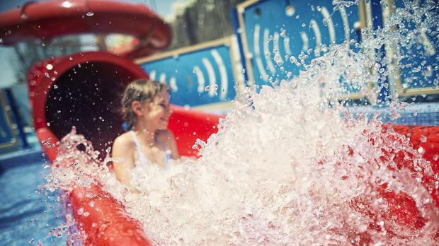 Water Slide Little girl having fun sliding on water slide in water park. The girl is aged 9. Focus on the splash the girl is out of focus.
