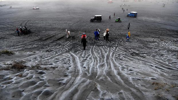 Pengunjung melintas di hamparan pasir yang diselimuti empun upas di kawasan Gunung Bromo, Probolinggo, Jawa Timur, Minggu (30/6/2019). Fenomena embun upas tersebut disebabkan penurunan suhu yang mencapai 0 derajat celcius pada malam hari. ANTARA FOTO/Zabur Karuru/hp.