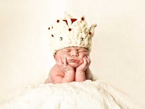 Newborn baby boy sleeping sleeping in a comfortable blanket wearing a white crown