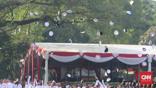 Para perwira melemparkan topi ke udara sebagai ungkapan kegembiraan kelulusannya dari akademi.