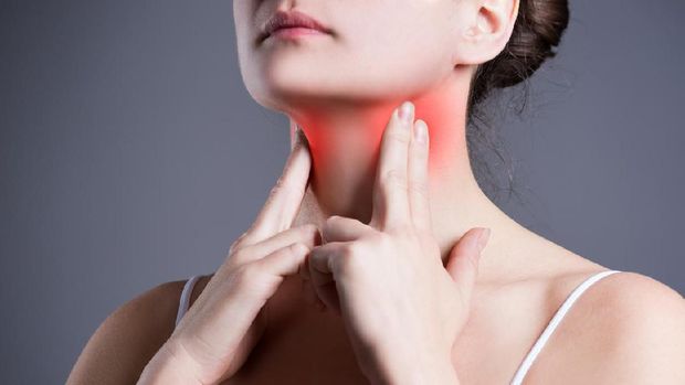 Sore throat, woman with pain in neck, gray background, studio shot