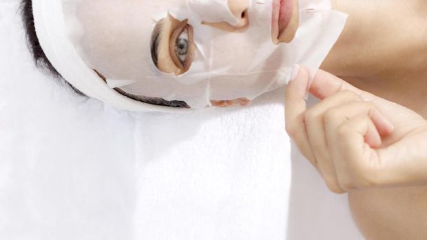 Caucasian female is taking off facial mask.