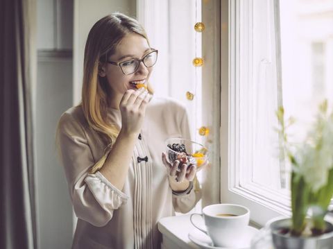 Young woman at home eating dates fruit