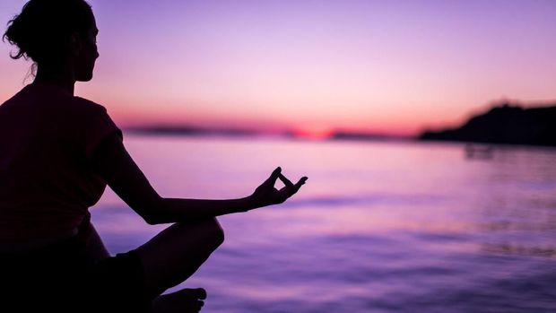 Calm Mindful Woman Meditating On Beach Faced Towards Majestic Sunset