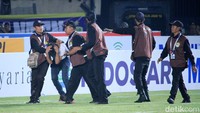 Petugas mengamankan suporter yang menerobos memasuki lapangan.