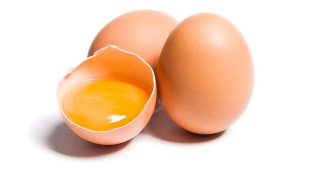 Group of brown raw chicken eggs, one is broken, yolk egg visible, isolated on white, studio shot.