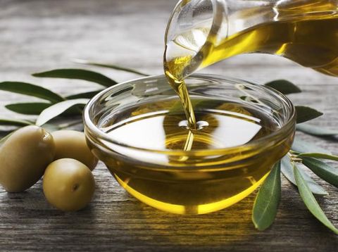 Bottle pouring virgin olive oil in a bowl close up