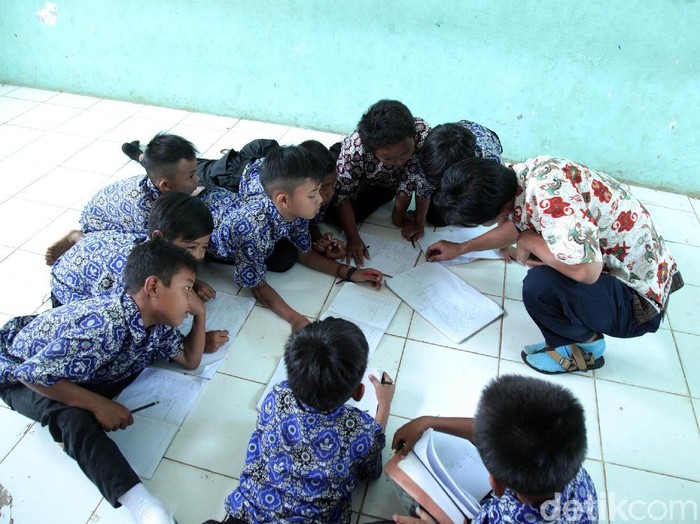 Seorang guru saat mengajar muridanya di lantai karena kekurangan bangku dan meja di Sekolah Dasar Negeri (SDN) Tegal 04, Kemang, Kabupaten Bogor, Jawa Barat, Rabu (31/7/2019). Kekurangan meja dan bangku di SDN 04 Tegal sudah hampir dua tahun lalu sehingga murid terpaksa belajar di lantai, bahkan pihak sekolah sudah mengusulkan ke Dinas Pendidikan Kabupaten Bogor namun belum ada realisasinya.