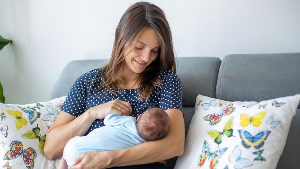 Young mother breastfeeding  her newborn baby boy at home