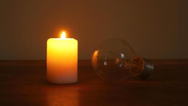 Burning candle and lamp on desktop in darkness (no electricity). Troubles with electricity after storm.