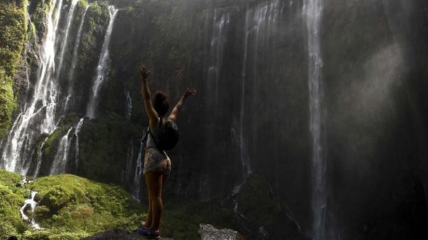 Pengunjung mengamati Air Terjun Tumpak Sewu di Lumajang, Jawa Timur, Minggu (4/8/2019). Air Terjun Tumpak Sewu merupakan air terjun dengan tinggi sekitar 120 meter yang berada di perbatasan Lumajang dengan Malang. ANTARA FOTO/Zabur Karuru/wsj.