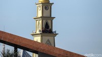 Beberapa pendukung PSM menonton pertandingan dari menara masjid di sekitar stadion.