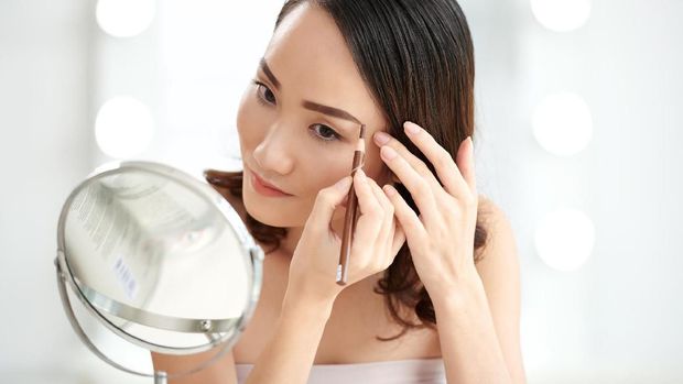 Chinese young woman filling her eyebrows