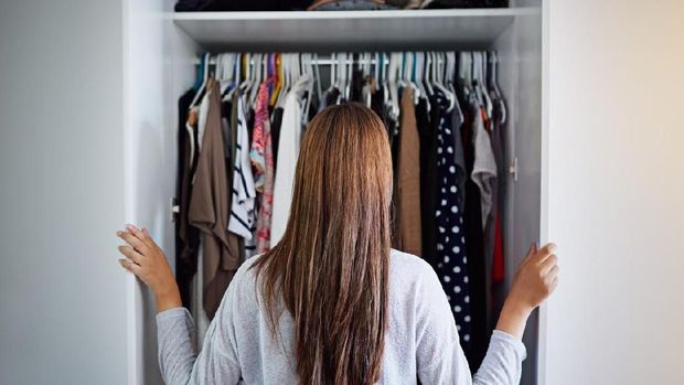 Rearview shot of a young woman standing in front of her closet choosing something to wear