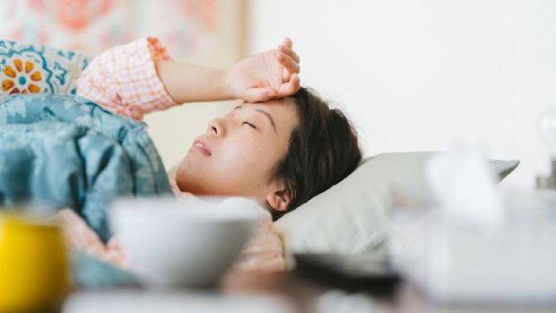 A women is feeling sick and sleeping on a sofa at home.