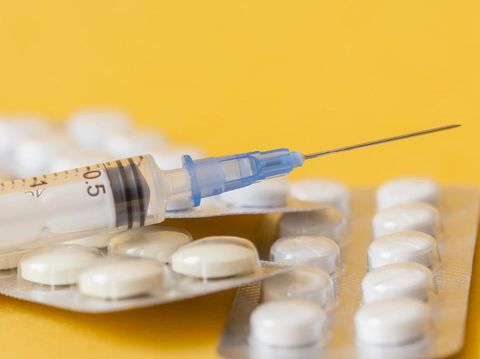 macro photo of tablets and syringe on yellow background. close up image