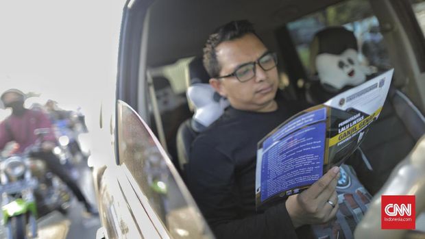 Pengendara membaca selebaran sosialisasi ganjil genap.
