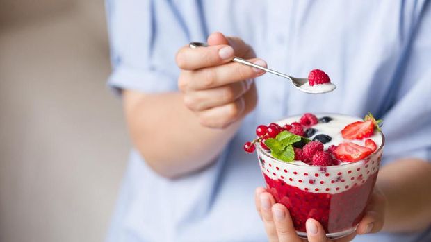 Woman  holding smoothie bawl with organic yogurt, berries and mint. Homemade yogurt in girl's hands served with raspberry, strawberry and blueberry. Breakfast. snack. Healthy eating, lifestyle concept