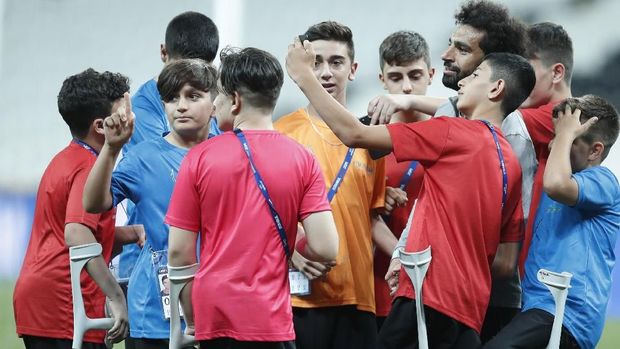 Liverpool's Mohamed Salah takes photographs with children at the end of a training session at the Besiktas Park Stadium, in Istanbul, Tuesday, Aug. 13, 2019. The winners of Champions League, Liverpool and Europa League, Chelsea will play at the Super Cup soccer match on Wednesday. (AP Photo/Thanassis Stavrakis)