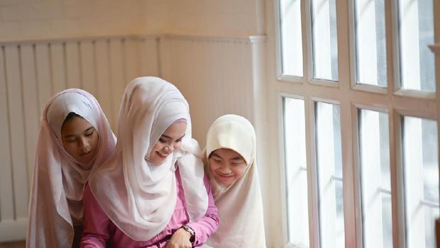 Young Asian Muslim teaching her sister to reading a book