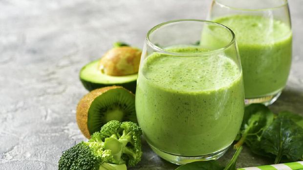 Green smoothie with avocado,broccoli,spinach,kiwi and apple in a glasses on a grey slate,stone or concrete background.