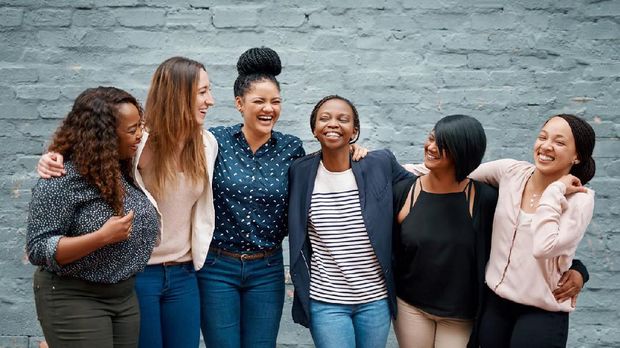 Portrait of a diverse group of young women standing together against a gray wall outside