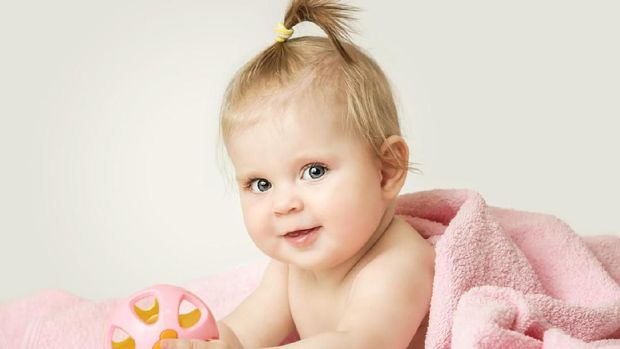 Studio portrait of adorable baby girl playing with plastic rattle toy