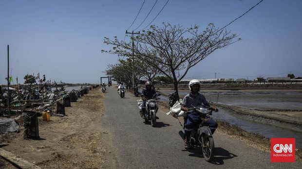 Warga menggunakan motor untuk mengangkut karung yang berisi tumpahan minyak mentah.