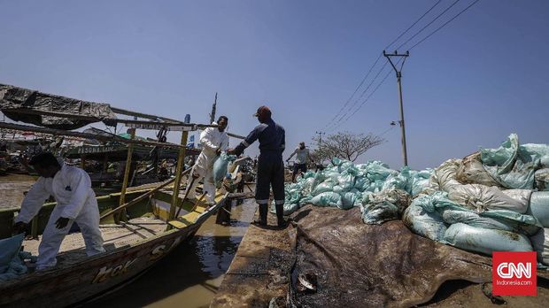 Warga membawa karung berisi pasir yang tercemar tumpahan minyak mentah (Oil Spill) di pesisir Pantai Cemarajaya, Karawang.