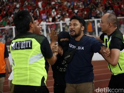 Petugas keamanan mengamankan suporter yang berusaha memasuki lapangan.