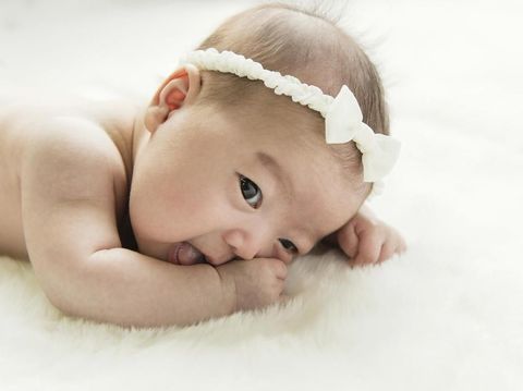 Cute newborn baby girl lying in the bed. 2 month old child in owl hat sleeping on blue blanket with stars