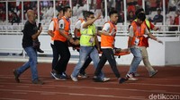 Salah satu suporter ditandu ke pinggir lapangan.