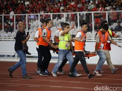 Salah satu suporter ditandu ke pinggir lapangan.