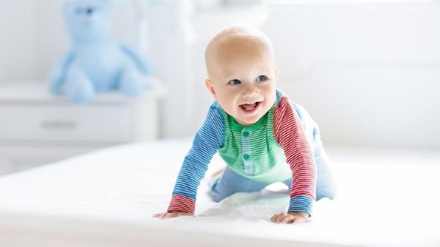 Cute toddler child, baby boy, playing with colorful toy in sunny bedroom, flag banner decoration behind him