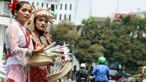 Massa yang tergabung dalam Masyarakat Penegak Demokrasi (MPD) memakai pakaian adat daerah, menggelar aksi budaya dengan membagikan bunga kepada pengendara yang melintas, di Jalan Medan Merdeka Barat, Jakarta, Senin (09/09/2019). Dalam aksinya mereka mendukung revisi Undang-Undang KPK dalam rangka memperkuat langkah pemberantasan korupsi.