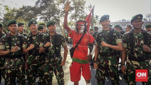 Pendukung Indonesia Muhammad Kurniawan di tengah petugas keamanan unsur TNI di GBK. (