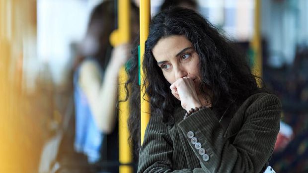 Pensive young woman traveling with bus and holding smart phone. Wears casual clothes.