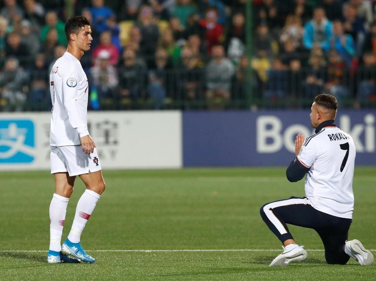 Fans Lithuania berlutut di depan Cristiano Ronaldo, saat striker Portugal itu ditarik keluar dari laga melawan Lithuania di Stadion LFF, Rabu (11/9) dini hari WIB. (Foto: Ints Kalnins/REUTERS)