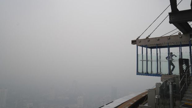 A staff waits at Skybox at Kuala Lumpur Tower as city stands shrouded with haze in Kuala Lumpur, Malaysia, Friday, Sept. 13, 2019. Malaysian authorities plan to conduct cloud-seeding activities to induce rain to ease the haze. The government said it will press Jakarta to take immediate action to put out the burning forests and ensure the fires won't occur again. (AP Photo/Vincent Thian)