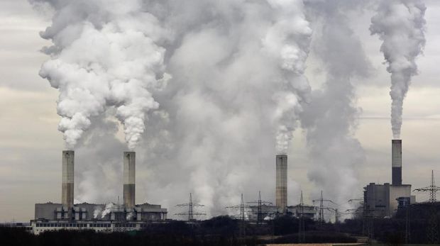 Smokestacks of a coal burning power plant with pollution on a cloudy day.