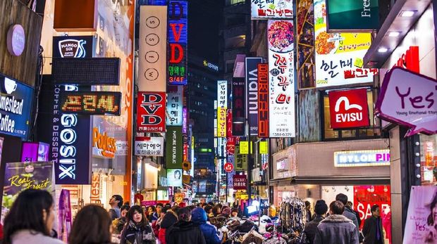 Seoul, South Korea - February 14, 2013: Crowds pass under the Myeong-Dong neon lights. The location is the premiere district for shopping in the city.