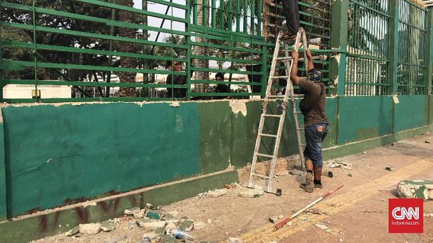 Pagar depan gedung DPR tampak sednag dibetulkan petugas setelah sehari sebelumnya digoyang massa.
